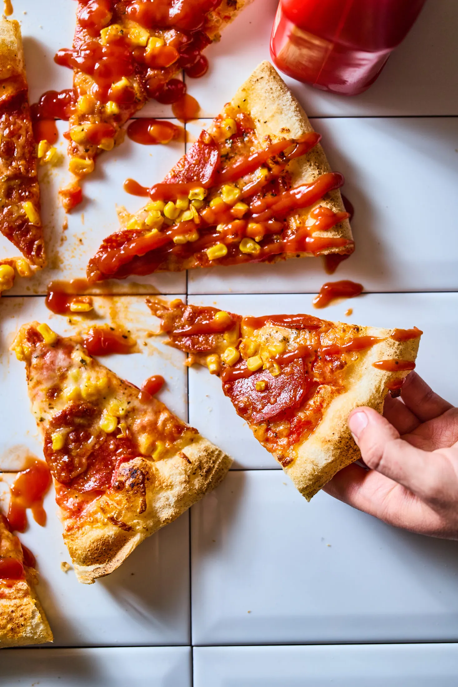 Szalámis kukoricás pizza szeletekre vágva ketchuppal