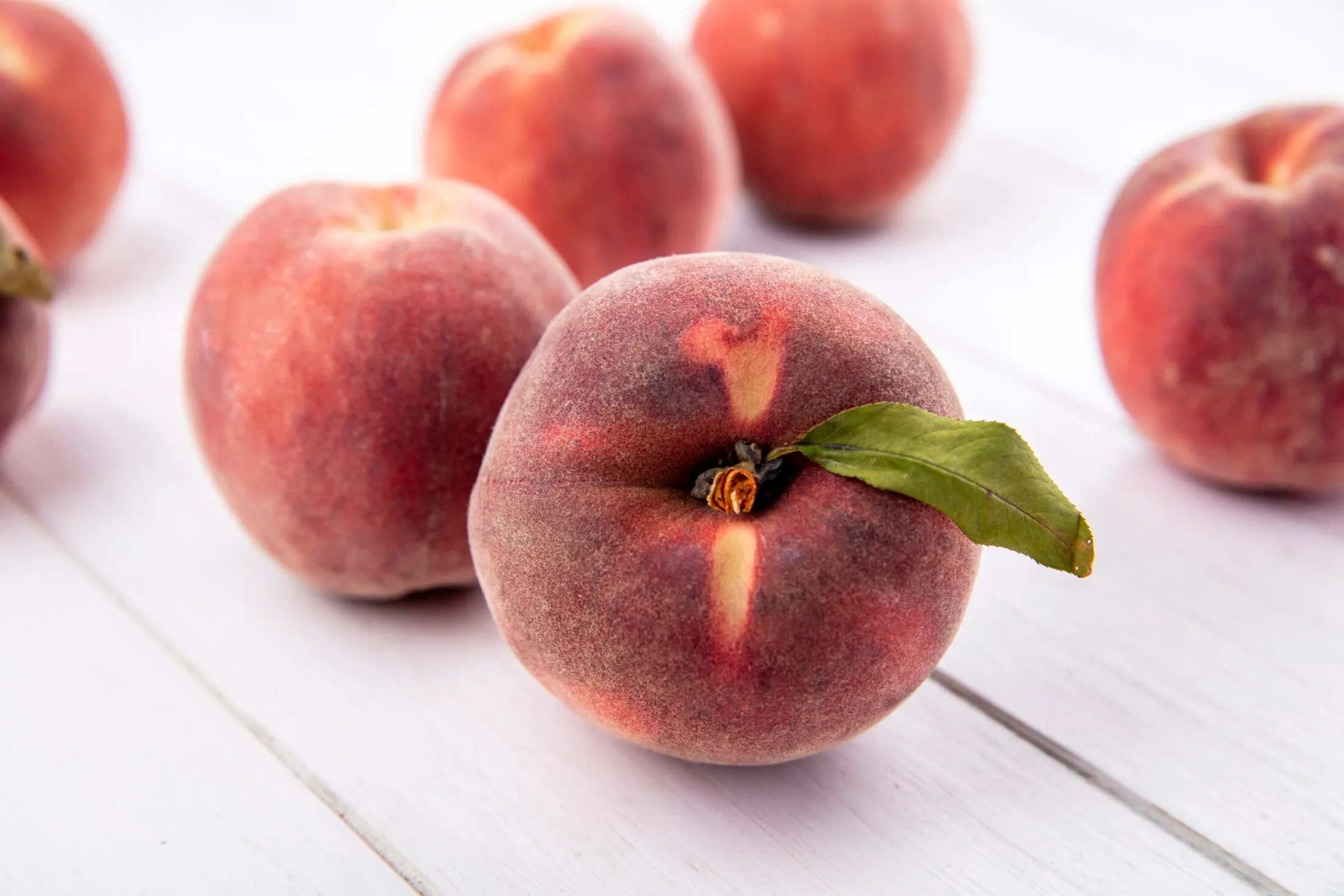 top-view-juicy-delicious-fresh-peaches-with-leaves-isolated-white-surface-scaled